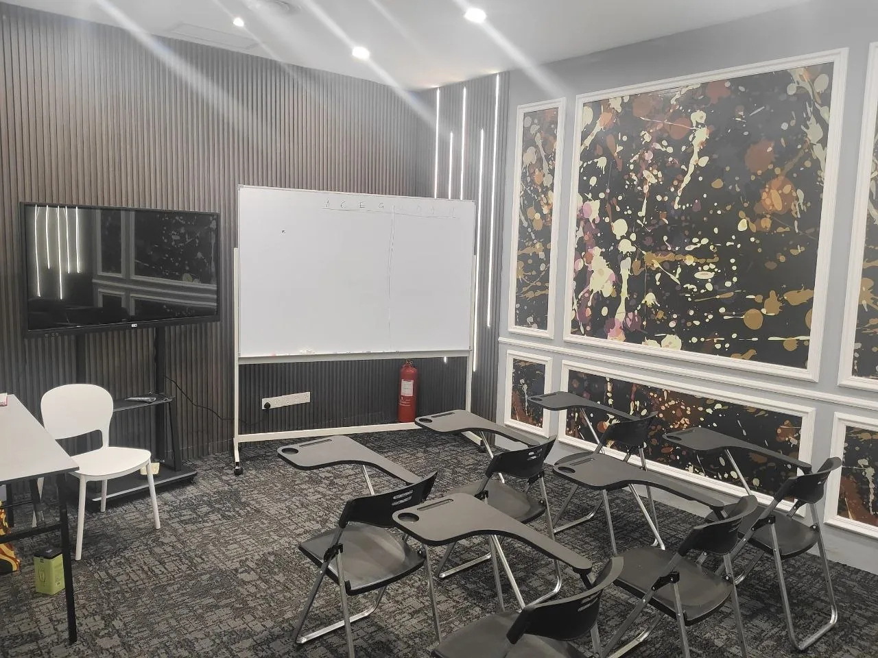 A modern, well-equipped Lingua Nova classroom with a whiteboard, screen and seating.