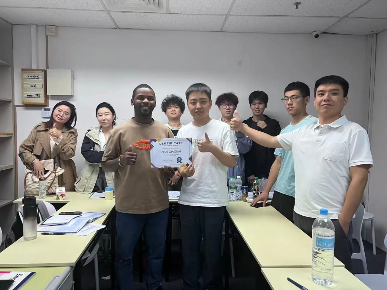 A group of adult students and teachers celebrating with a completion certificate.