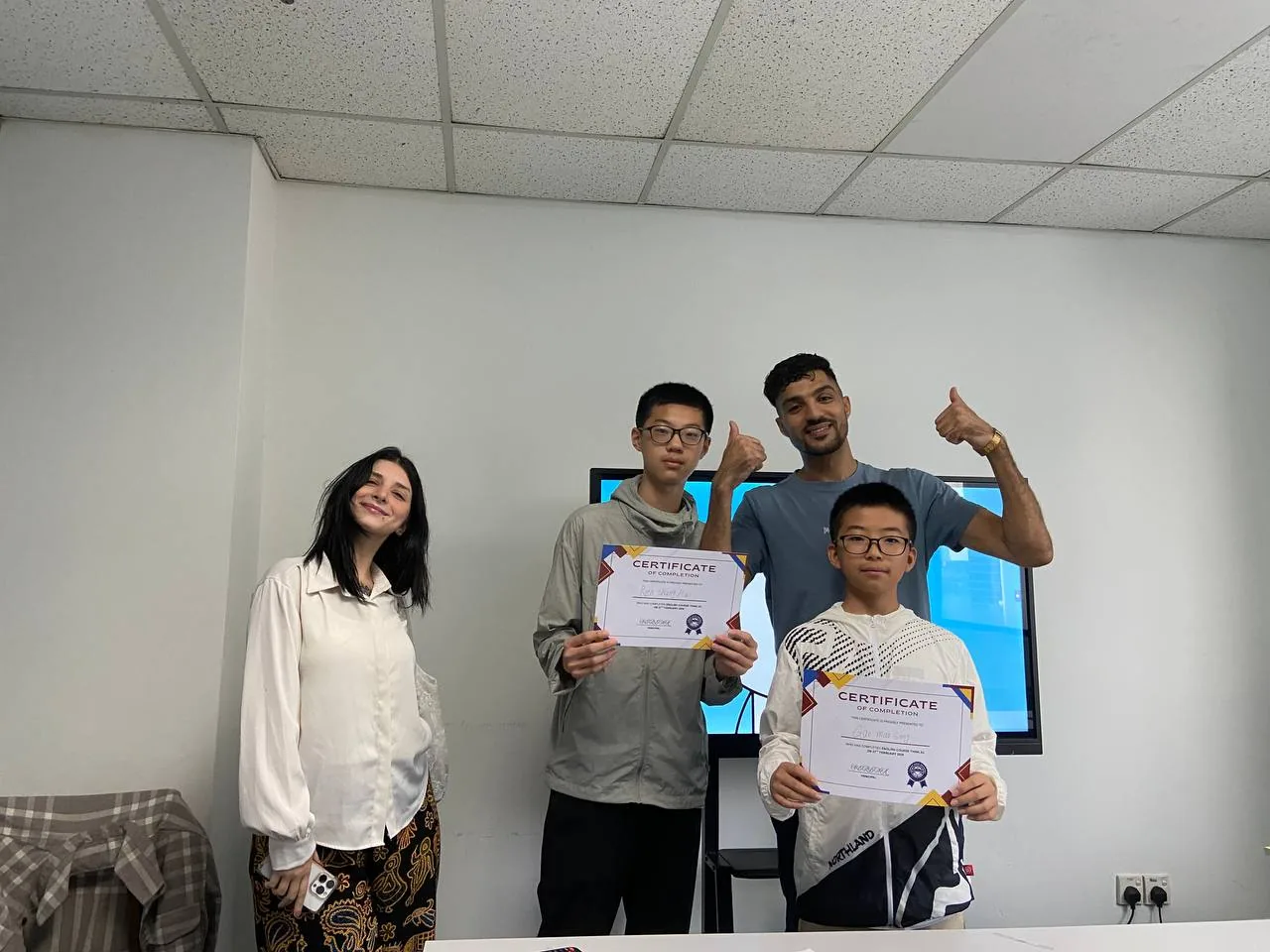 Two teenage students receiving completion certificates with their teachers.
